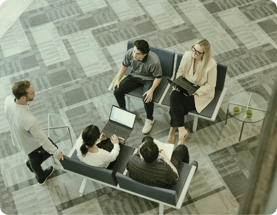 Five individuals seated on chairs in an office setting, participating in a collaborative meeting.